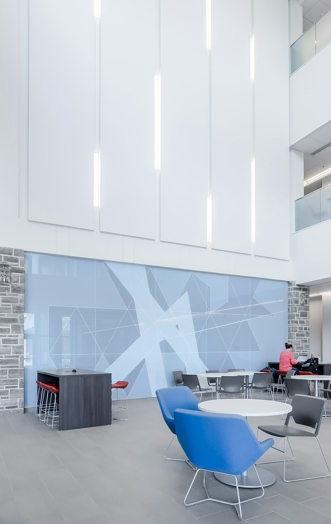 student of Nursing studies in the new FIMS & Nursing Building at Western University. She looks especially small and showcases the scale of the light and open atrium. Building designed by architects Tillmann Ruth Robinson in London, Ontario.